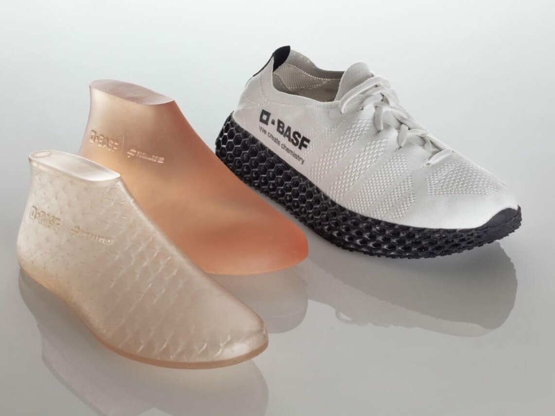 Two 3d printed, slightly transparent molds (Left: Printed with infill Right: Full material print.) next to a white sneaker with BASF logo and anthracite colored sole.