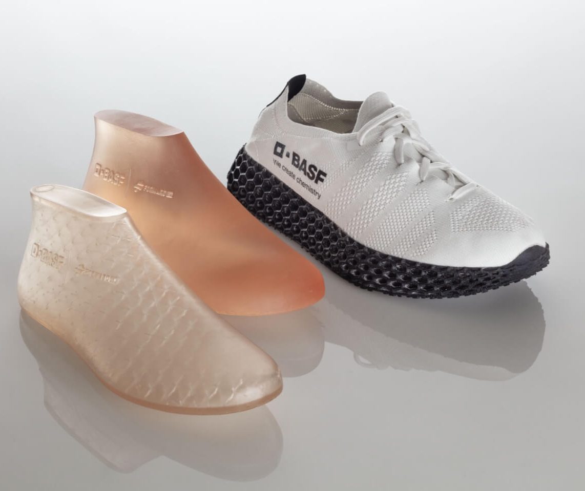 Two 3d printed, slightly transparent molds (Left: Printed with infill Right: Full material print.) next to a white sneaker with BASF logo and anthracite colored sole.