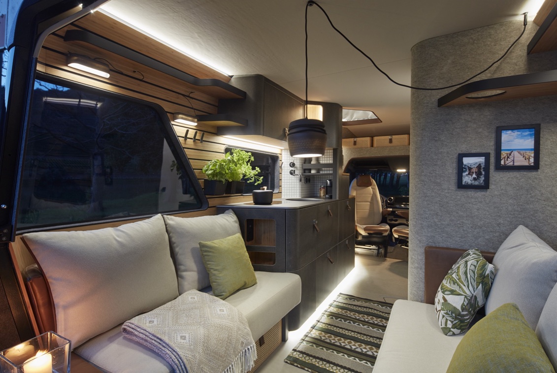 The interior of the VisionVenture Concept Van with 3D printed lamp, seating in beige tones and indirect lighting.
