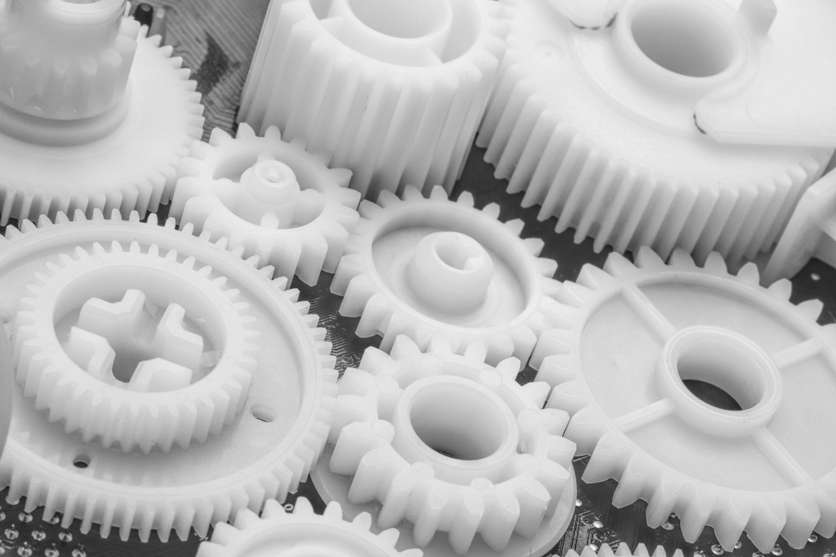 Close up of white plastic gears of different sizes.