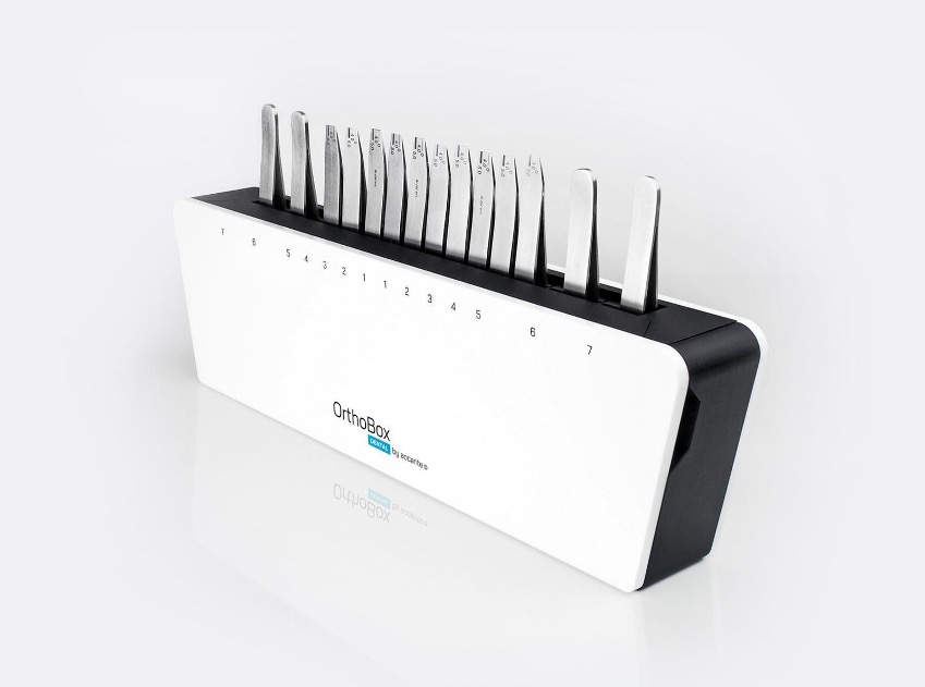 A white box from which the ends of orthodontic devices (metal tweezers) look out at the top.