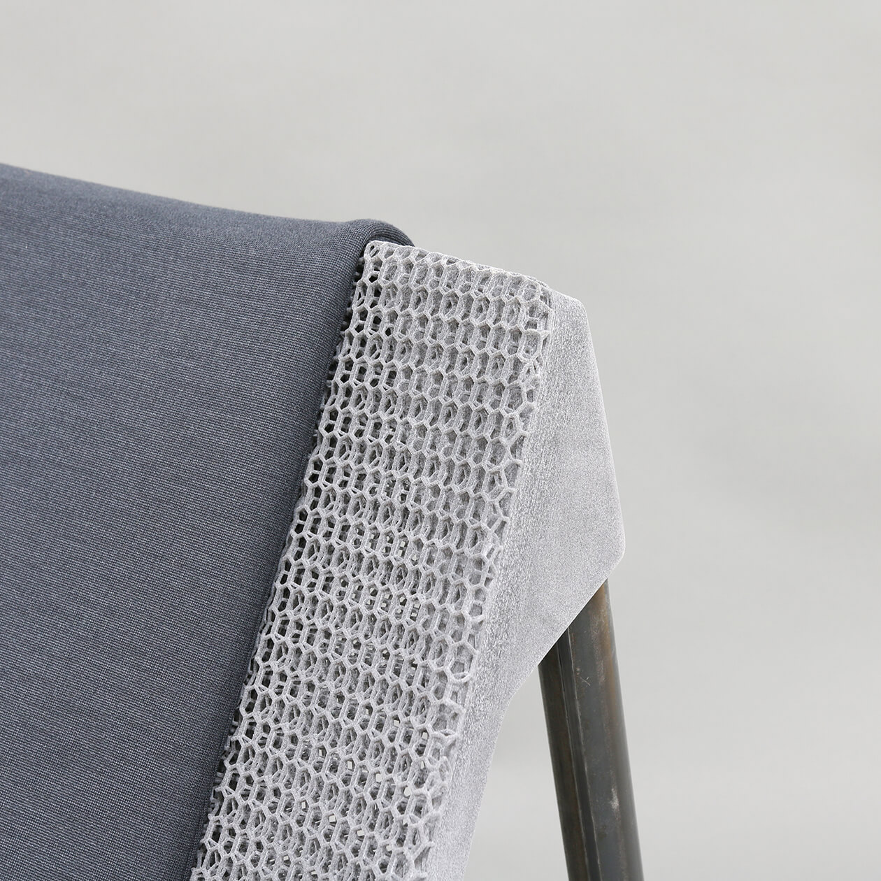 Close-up of a lounge chair with a lattice-structured backrest and a dark gray seat cushionray upholstery.